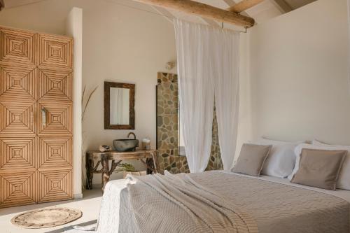 a white bedroom with a bed and a mirror at Spathes Suites Kefalonia - Luxury Suites in Ratzaklíon