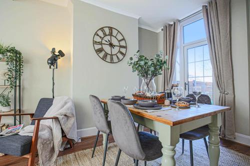 a dining room with a table and chairs with a clock on the wall at Two Bedroom Home in Northampton by HP Accommodation - Free Parking & WiFi in Northampton