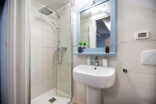 a white bathroom with a sink and a shower at Casa Polo in Rovinj