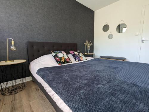 a bedroom with a large bed with a blue blanket at Le Boudoir d'Emma - Jacuzzi privatif - Détente - Massage in Alençon