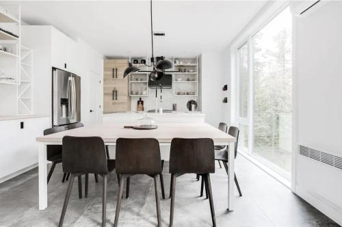 a white kitchen with a dining table and chairs at Allen Falls, chalet avec spa in Morin Heights