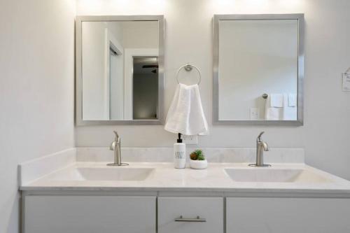 a bathroom with two sinks and two mirrors at Charming DT 3-Bed Bungalow with Fenced-in Yard in Raleigh