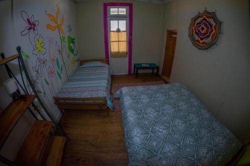 Cette chambre comprend 2 lits et une fenêtre. dans l'établissement Bichon La Casa Hostal, à Pichilemu