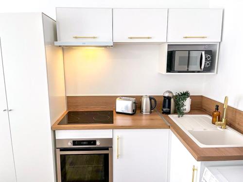 une cuisine avec des armoires blanches et un four à plaques de cuisson dans l'établissement Le Petit Martial - coeur de ville,refait à neuf,tout équipé, parking, à Châteauroux