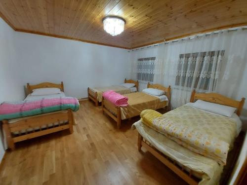 a room with three beds and a wooden floor at Guest House Trojani in Lëpushë