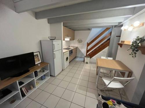una pequeña cocina con mesa y nevera en Maison 400m plage, en Mimizan