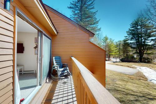 a wooden porch with two chairs on the side of a house at Nordic Wilderness Lodge in Bartlett