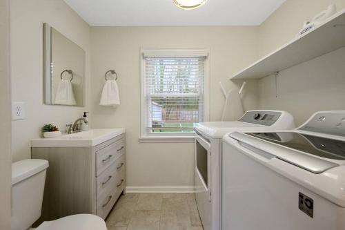 uma casa de banho branca com um lavatório e uma máquina de lavar roupa em Cozy 3 Bedroom Cottage with Huge Fenced-In Yard em Raleigh