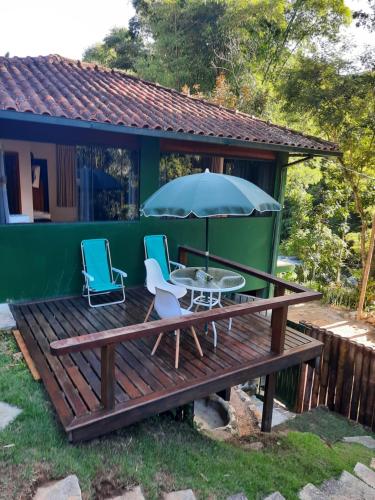 a wooden deck with two chairs and an umbrella at venha curtir a natureza in Nova Friburgo