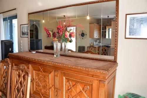 a mirror on top of a wooden cabinet with flowers on it at Μπουκαμβίλια/Bougainvillea tree in Vaia