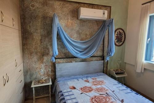 a bedroom with a bed with a blue drape at Μπουκαμβίλια/Bougainvillea tree in Vaia