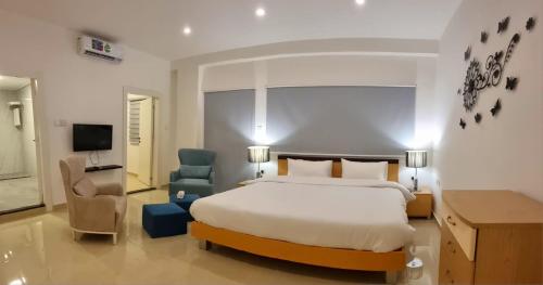 ein Schlafzimmer mit einem Bett, einem Stuhl und einem TV in der Unterkunft Byblos Deluxe in Aqaba