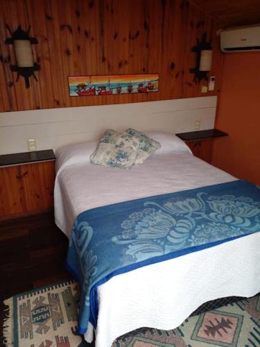1 dormitorio con 1 cama con manta azul y blanca en Cabañas Punta Palmar (Casa 3) en Punta del Diablo