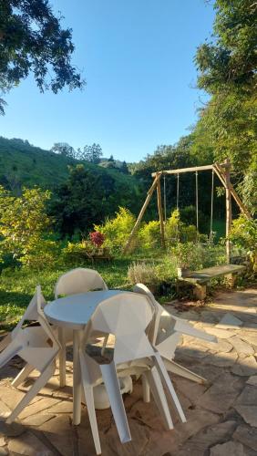 a table and chairs sitting next to a swing at Recanto Águas Claras in Soledade de Minas
