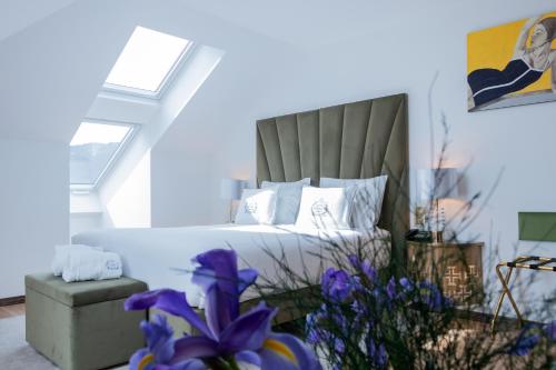 ein Schlafzimmer mit einem Bett und einem Stuhl sowie lila Blumen in der Unterkunft Hotel República Boutique Hotel in Tomar