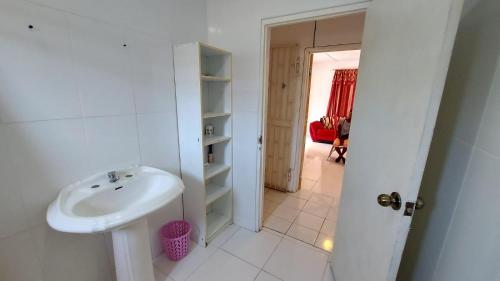 Habitación y baño blanco con lavabo. en Charming 1-Bedroom House in St Thomas Jamaica, en Belfast