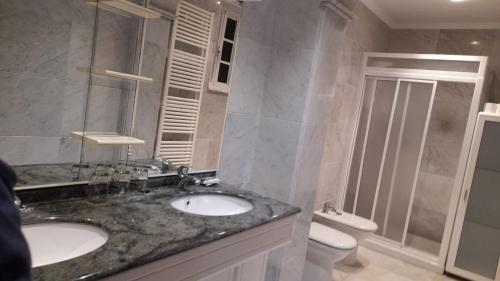 a bathroom with two sinks and a shower and a toilet at Pension Grilo in Padrón