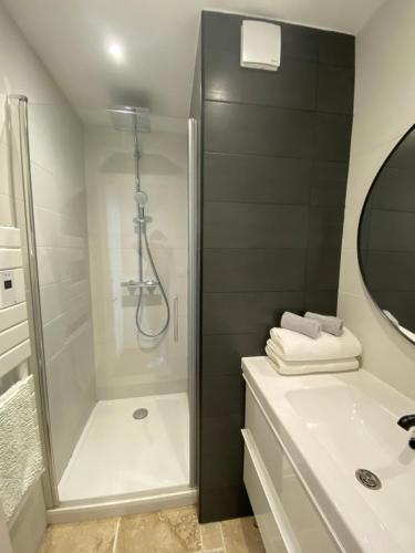 La salle de bains blanche est pourvue d'une douche et d'un lavabo. dans l'établissement Appartement vue sur l'océan, à La Parée Preneau