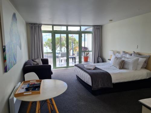 een hotelkamer met een groot bed en een tafel bij The Wharf Seaview Apartments by AVI in Akaroa