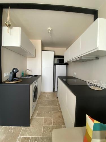 une cuisine avec des armoires blanches et un comptoir noir dans l'établissement Appartement vue sur l'océan, à La Parée Preneau