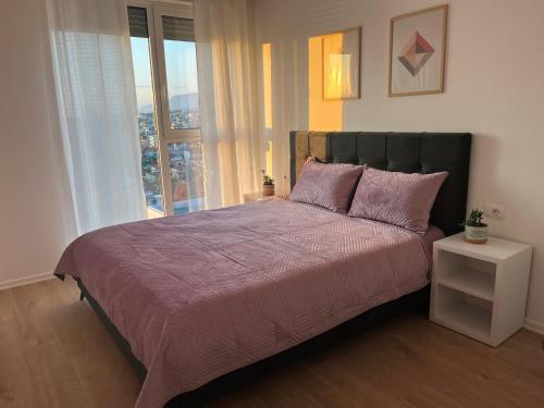 a bedroom with a large bed with a large window at Comfy Nest Apartment- free parking in Tirana