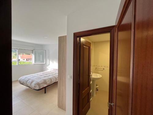 a bedroom with a bed and a door leading to a bathroom at Apartamento Prado in Finisterre