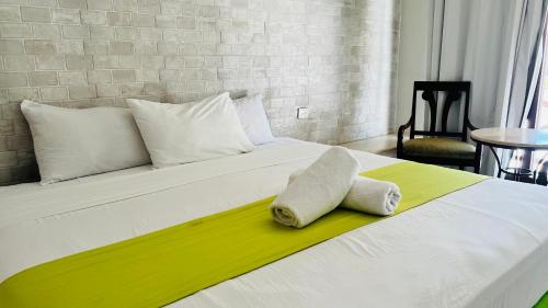 a white bed with a towel laying on it at Hotel MAYARI Holbox in Holbox Island