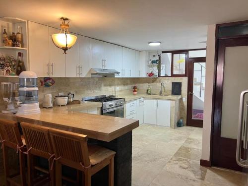 eine Küche mit weißen Schränken und einer hölzernen Arbeitsplatte in der Unterkunft Casa Villa Victoria en Pisco in Pisco