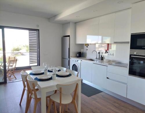 a white kitchen with a table and chairs in it at Apartamento Flow Living, com piscina, em Olhão in Olhão