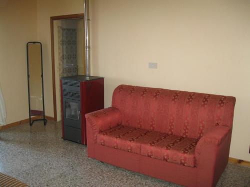 a red couch sitting in a room with a dresser at Appartamento le castagnelle in Copersito