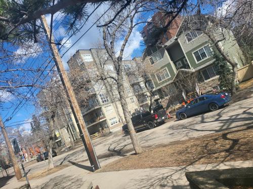 a blue car parked on a street in front of buildings at West Edmon. Mall = Room in Edmonton