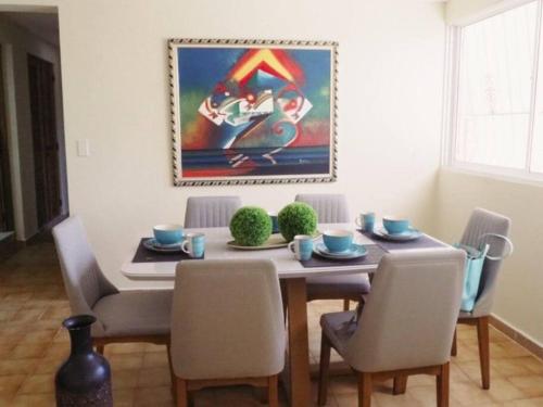 a dining room table with chairs and a painting on the wall at LA CASA DE MAMA LUZ in San Felipe de Puerto Plata