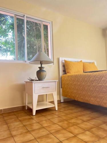 a bedroom with a bed and a table with a lamp at LA CASA DE MAMA LUZ in San Felipe de Puerto Plata