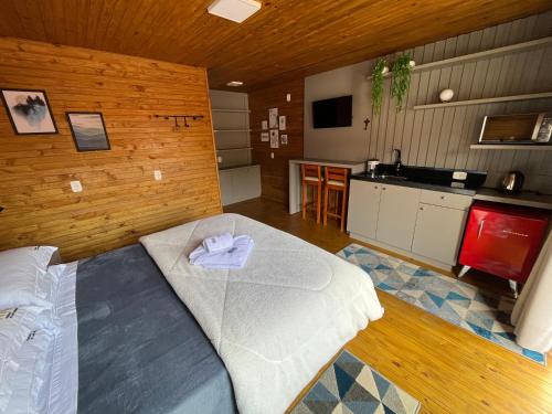 a bedroom with a large bed and a kitchen at POUSADA 05 LUAS URUBICI in Urubici