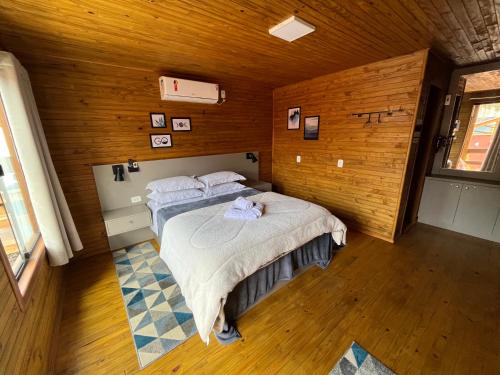 a bedroom with two beds in a room with wooden walls at POUSADA 05 LUAS URUBICI in Urubici