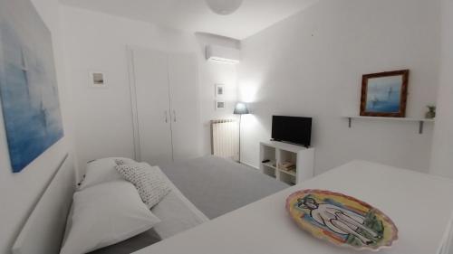 um quarto branco com uma cama, um sofá e uma televisão em Casetta Cirantò monolocale em Ischia
