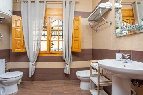 ein Badezimmer mit Waschbecken und Toilette und einem Fenster in der Unterkunft Casa Los Cortijillos in Alcaucín