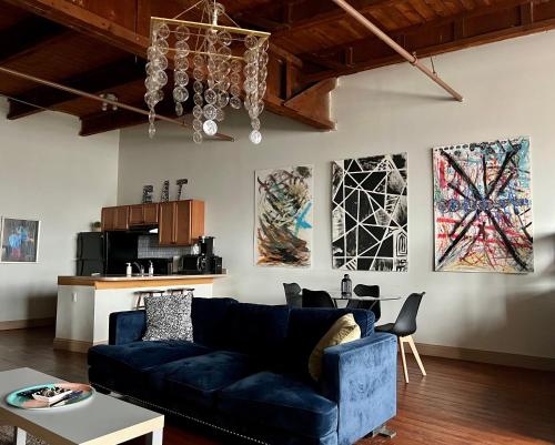 a living room with a blue couch and paintings on the wall at 420 Friendly Loft Skyline/Canada View Free Parking in Detroit