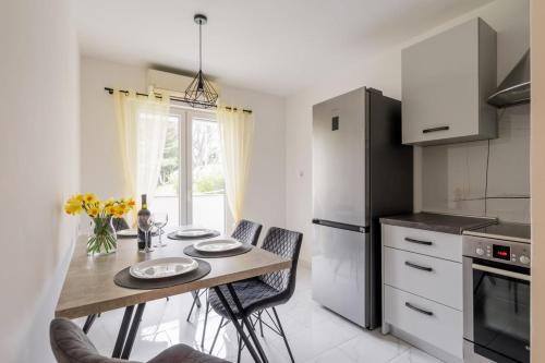 Una cocina con una mesa con sillas y un refrigerador. en Apartman Linnea, en Rijeka