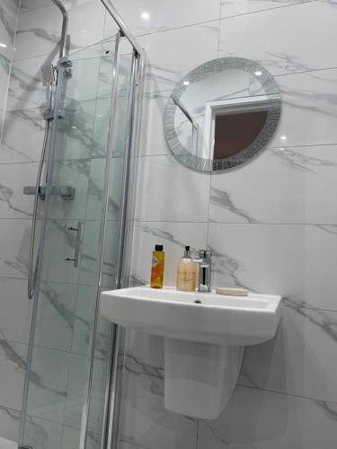 a white bathroom with a sink and a mirror at Grand Bleu - London - Next to Piccadilly Line Tube Station & Brand New Facilities in London