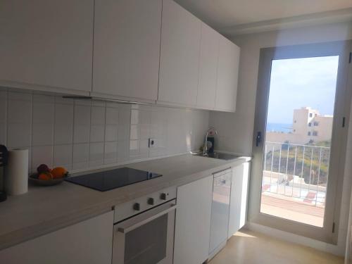 a kitchen with white cabinets and a large window at Luz de Mar. in Carboneras