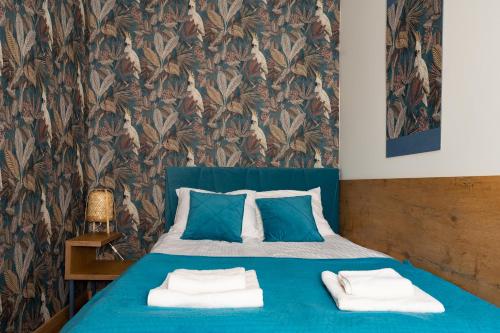 a bedroom with a blue bed with two towels on it at Apartament Inspirujący - z prywatnym monitorowanym parkingiem - 4 osobowy - Space Apart in Jelenia Góra