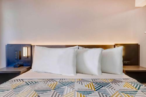 a bed with white pillows in a hotel room at Studio 6 Rock Springs WY Flaming Gorge in Rock Springs