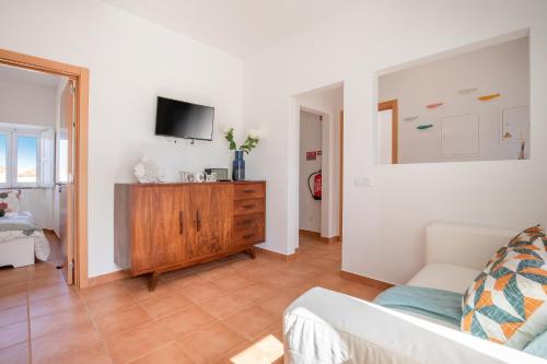 a living room with a couch and a tv on a wall at Casa 7 Gerações in Sagres