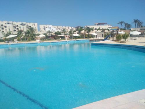 una gran piscina azul con edificios en el fondo en villa north coast, en El Alamein