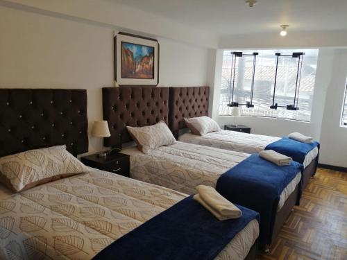 a bedroom with two beds with blue ottomans at Reservation Machupicchu Huascar in Cusco