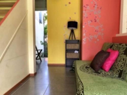 salon z zieloną kanapą i różowymi poduszkami w obiekcie Maison colibri w mieście Les Anses-d'Arlet
