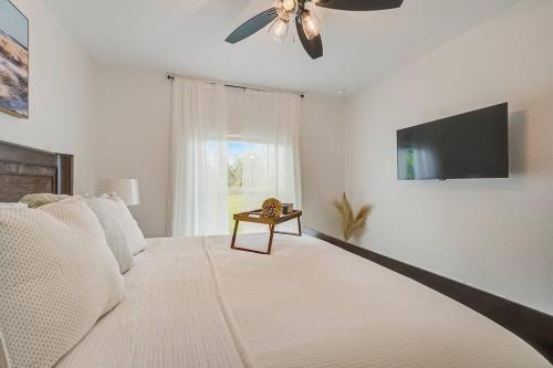 a bedroom with a bed with a ceiling fan and a window at Sunny Coastal,3 BD, 2 BA, King Master Suite, Close to Ocean, Golfing , Fishing in Rotunda-West