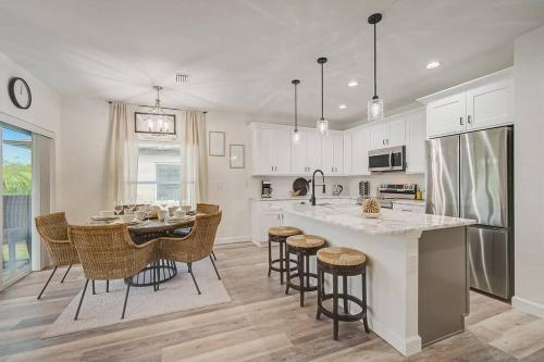 a kitchen with white cabinets and a table with bar stools at Sunny Coastal,3 BD, 2 BA, King Master Suite, Close to Ocean, Golfing , Fishing in Rotunda-West