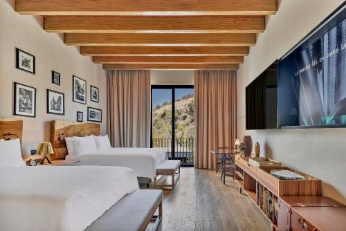 a hotel room with two beds and a television at Live Aqua San Miguel de Allende in San Miguel de Allende